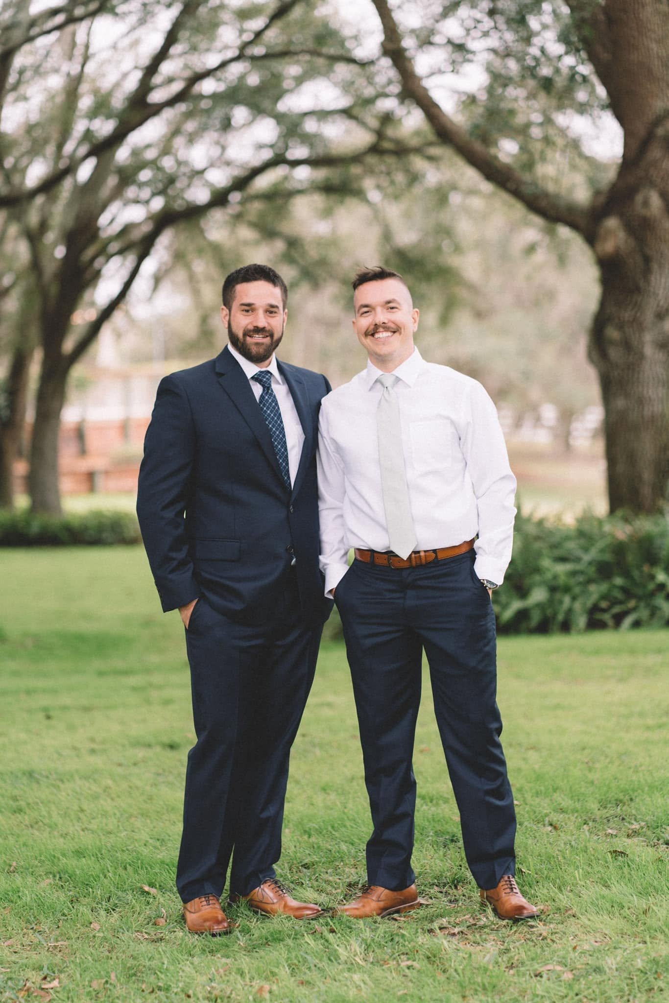 Trevor on the left in a navy suit and Mike Ullman on the right in a white shirt, standing together outdoors