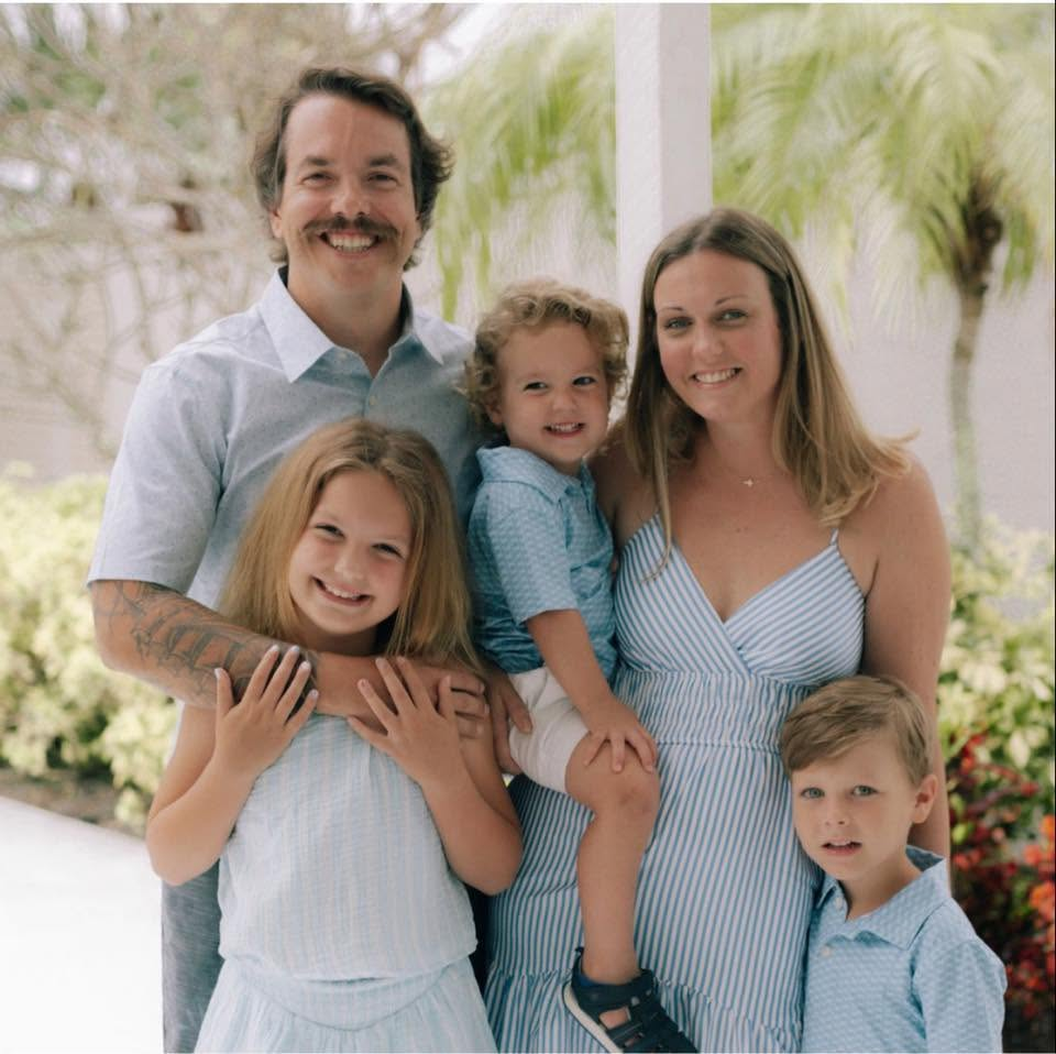 Mike and his family outdoors among palm trees